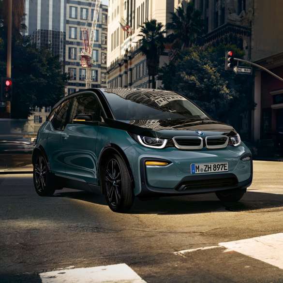 BMW i3 2018 three-quarter front view driving BMW i3 I01 2018 Jucaro beige with Frozen Grey metallic highlight three-quarter front view driving in urban setting
