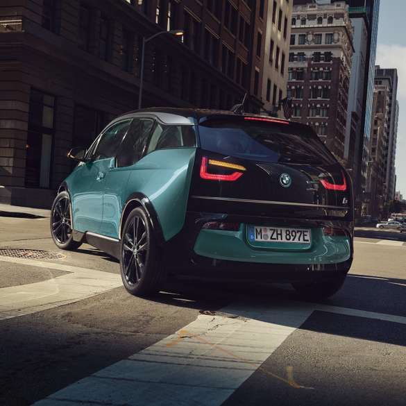 BMW i3 2018 three-quarter rear view driving BMW i3 I01 2018 Jucaro beige with Frozen Grey metallic highlight three-quarter rear view driving in urban setting