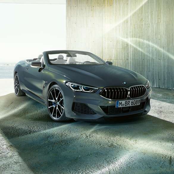 BMW M850i xDrive Convertible, three-quarter front view. BMW M850i xDrive Convertible in Dravit Grey metallic with open softtop, three-quarter front view, standing in front of coast.