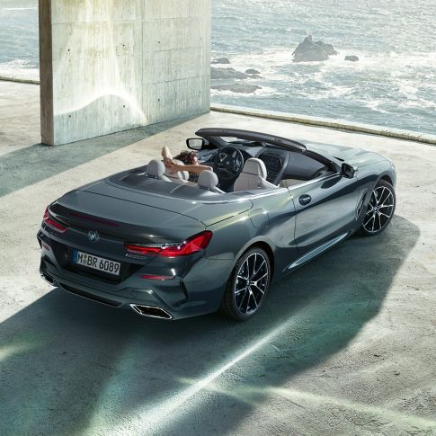 BMW M850i xDrive Convertible, bird's eye view. BMW M850i xDrive Convertible in Dravit Grey metallic with open softtop, bird's eye view, parking in concrete building in front of ocean.