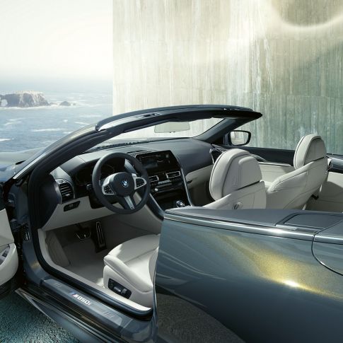 BMW M850i xDrive Convertible, interior. BMW M850i xDrive Convertible in Dravit Grey metallic with open softtop, interior with M leather steering wheel and BMW Individual leather trim 'Merino' Ivory White.