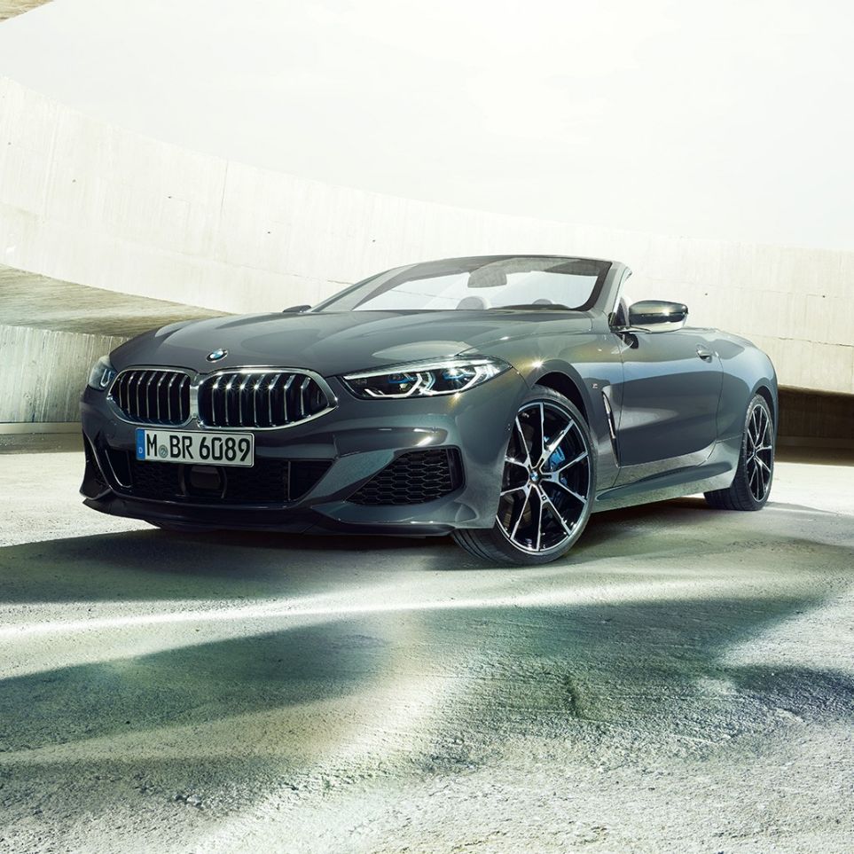 BMW M850i xDrive Convertible, three-quarter front view. BMW M850i xDrive Convertible in Dravit Grey metallic with open softtop, three-quarter front view, standing in concrete building.