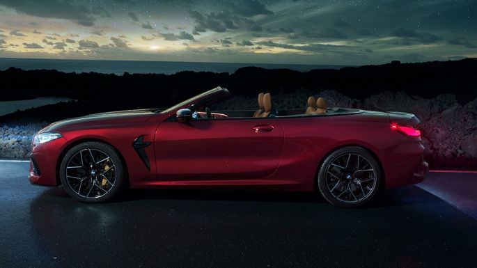 BMW M8 Competition Convertible, side view. BMW M8 Competition Convertible in Motegi Red metallic with open softtop, side view, standing at night under starry sky.
