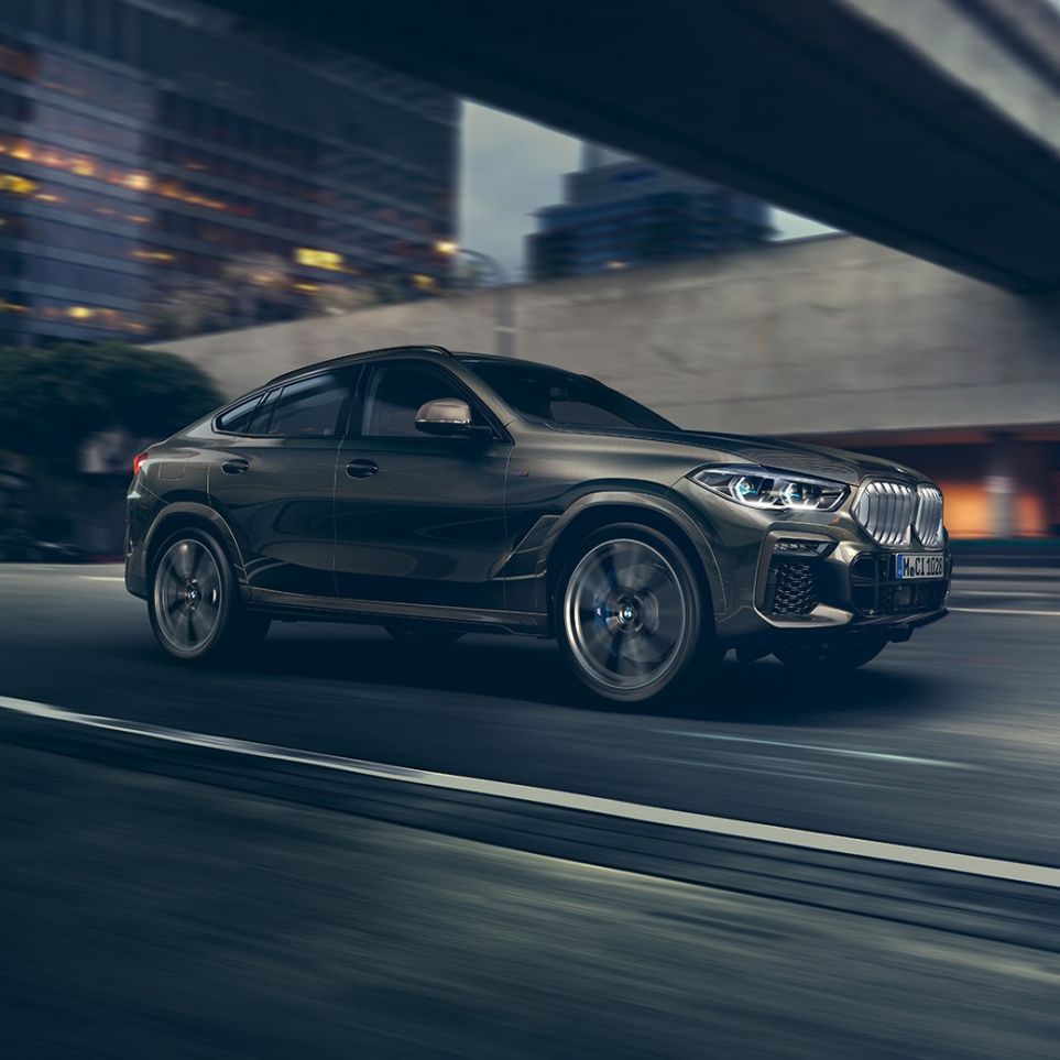 BMW X6 driving. BMW X6 in three-quarter front perspective driving in front of an urban setting.