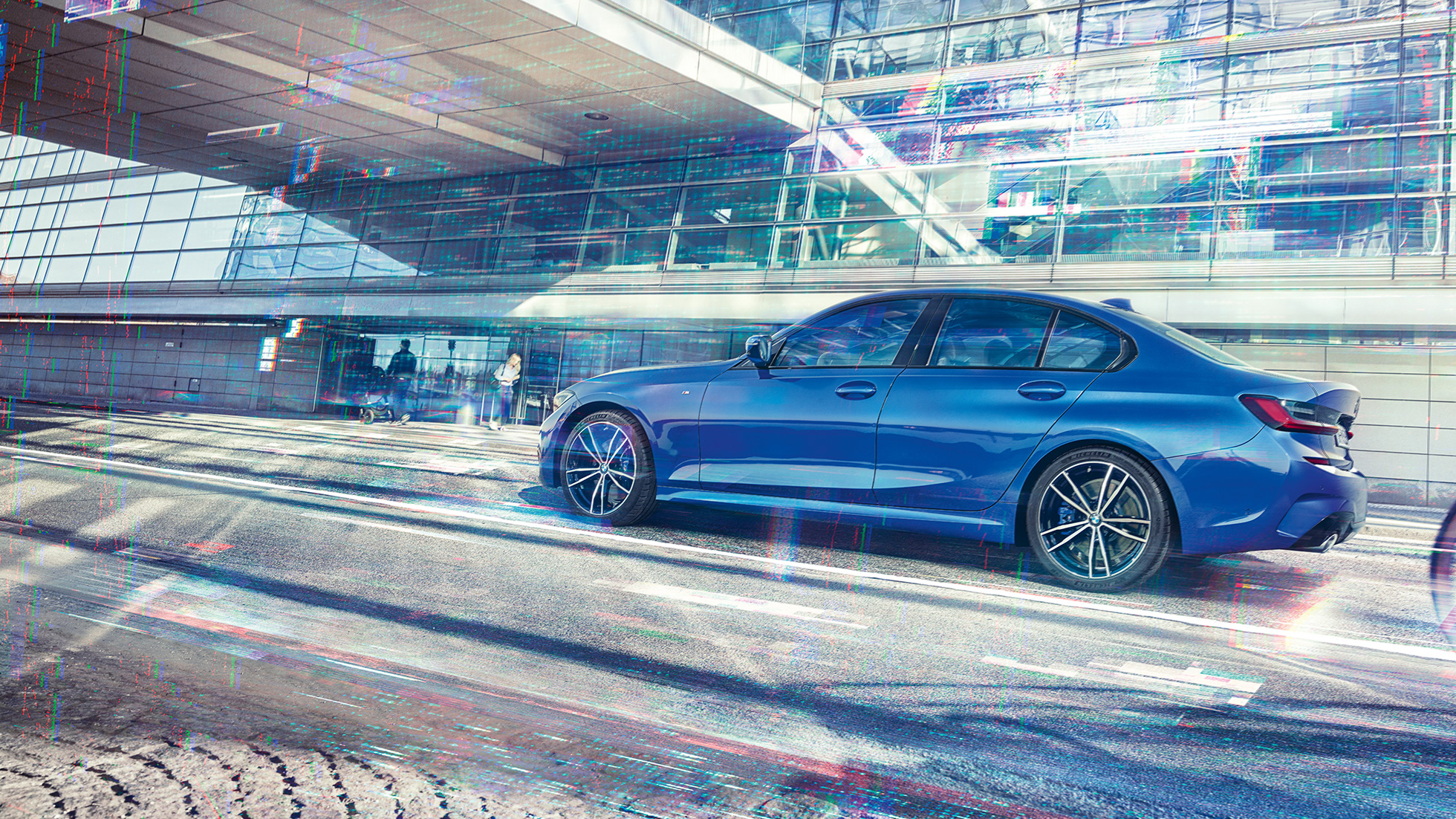 BMW 3 Series Sedan, side view. Still shot of the BMW 3 Series Sedan from the side on the day in front of a glass building.