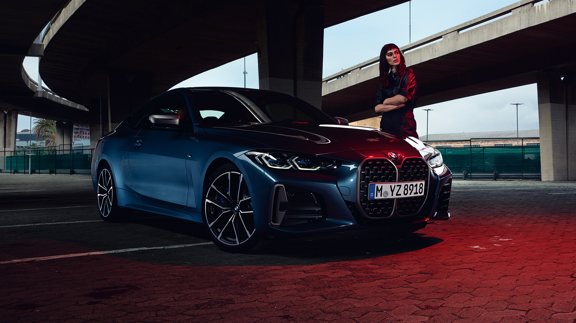 Model standing next to BMW M440i xDrive Coupé G22 2020 three quarter side view BMW M440i xDrive Coupé Arctic Race Blue metallic G22 2020 three quarter side view with model