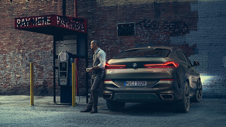 Man leaning on rear of the BMW X6 M50i.