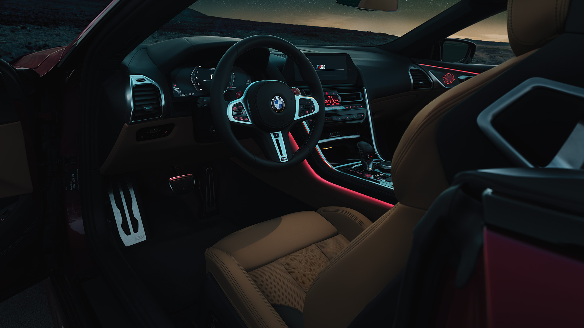 BMW M8 Competition Convertible, cockpit. BMW M8 Competition Convertible, cockpit by night with M leather steering wheel and red ambient light.