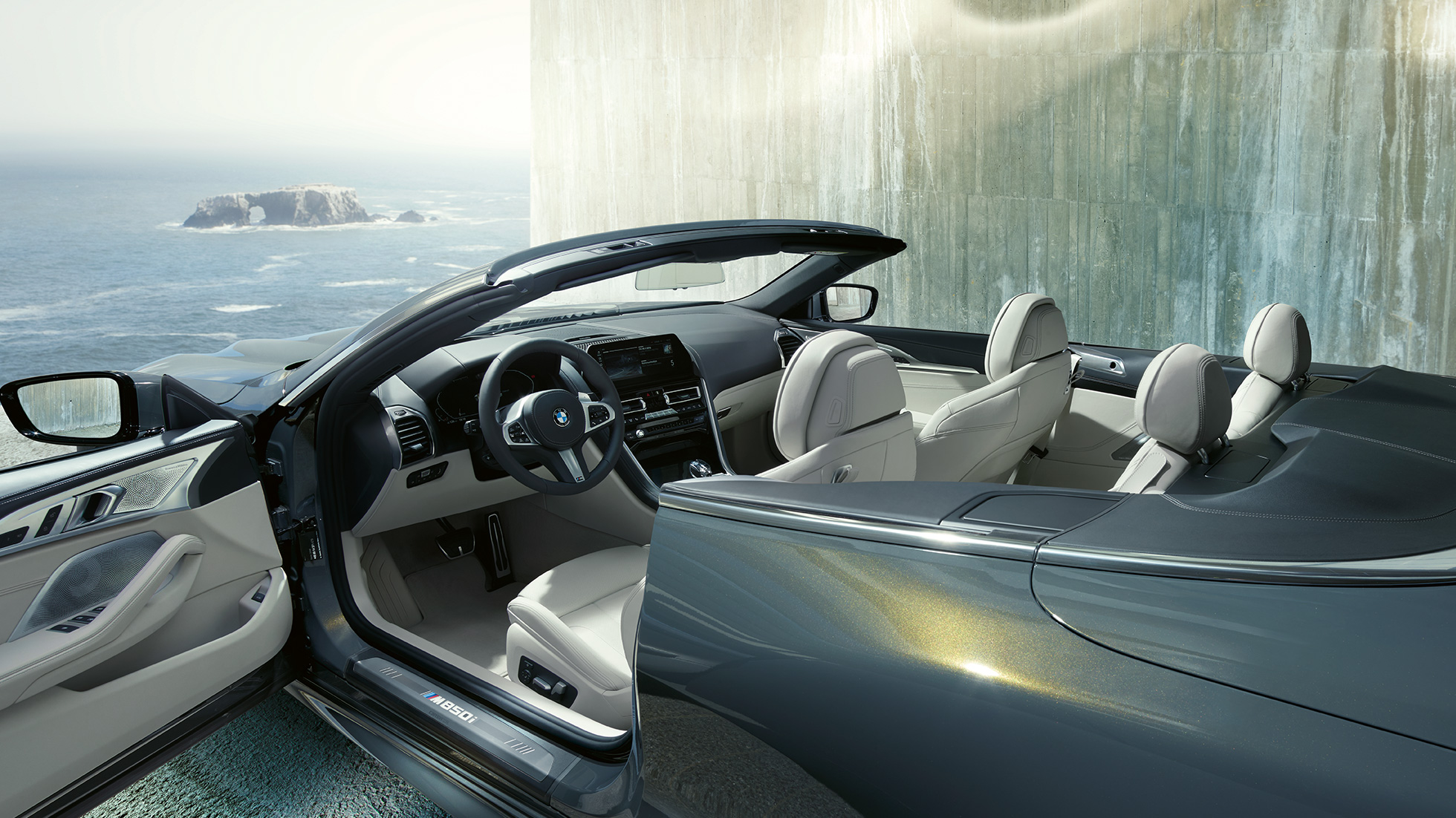 BMW M850i xDrive Convertible, interior. BMW M850i xDrive Convertible in Dravit Grey metallic with open softtop, interior with M leather steering wheel and BMW Individual leather trim 'Merino' Ivory White.