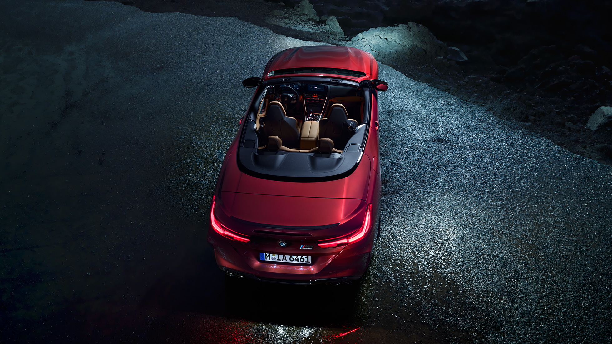BMW M8 Competition Convertible, bird’s-eye view. BMW M8 Competition Convertible in Motegi Red metallic with open softtop, bird’s-eye view, standing at night on asphalt.