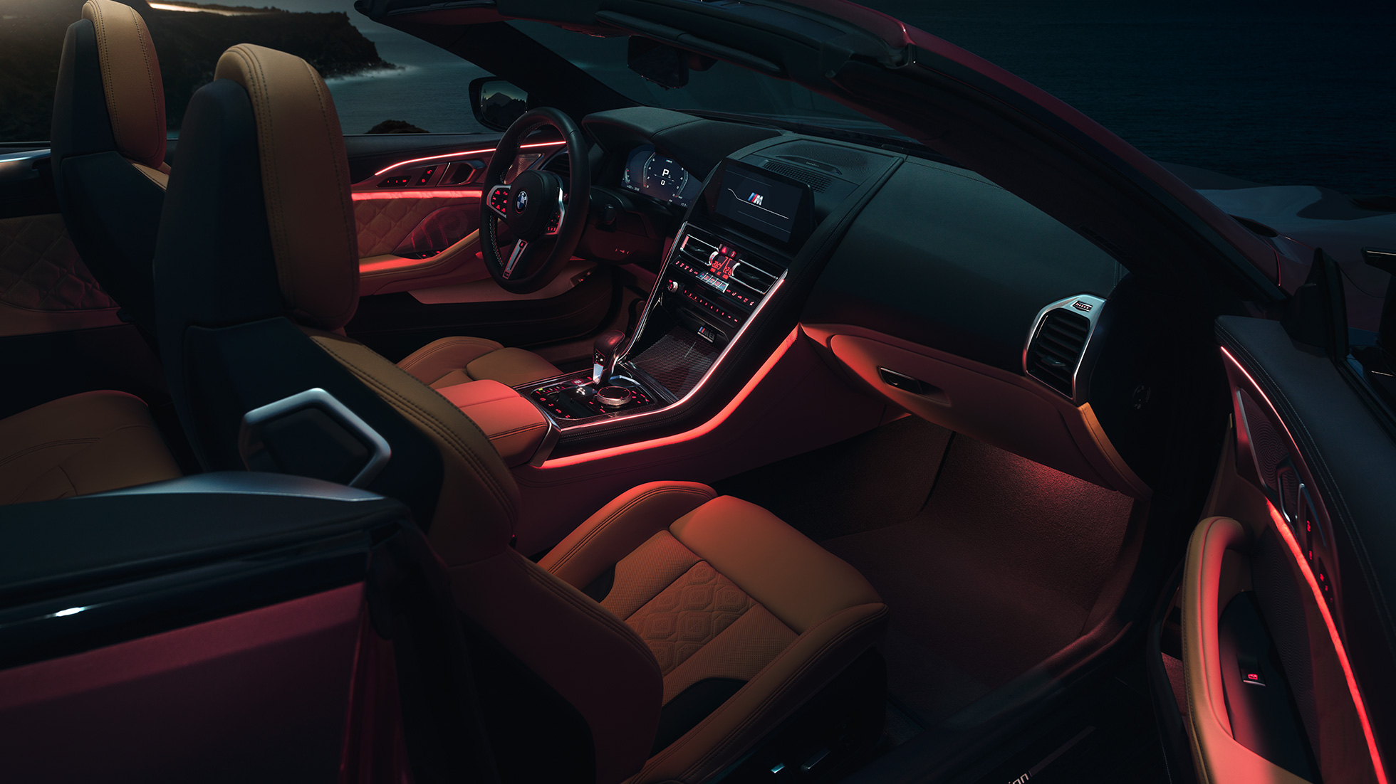 BMW M8 Competition Convertible, interior. BMW M8 Competition Convertible with open softtop, interior with red ambient light at night.