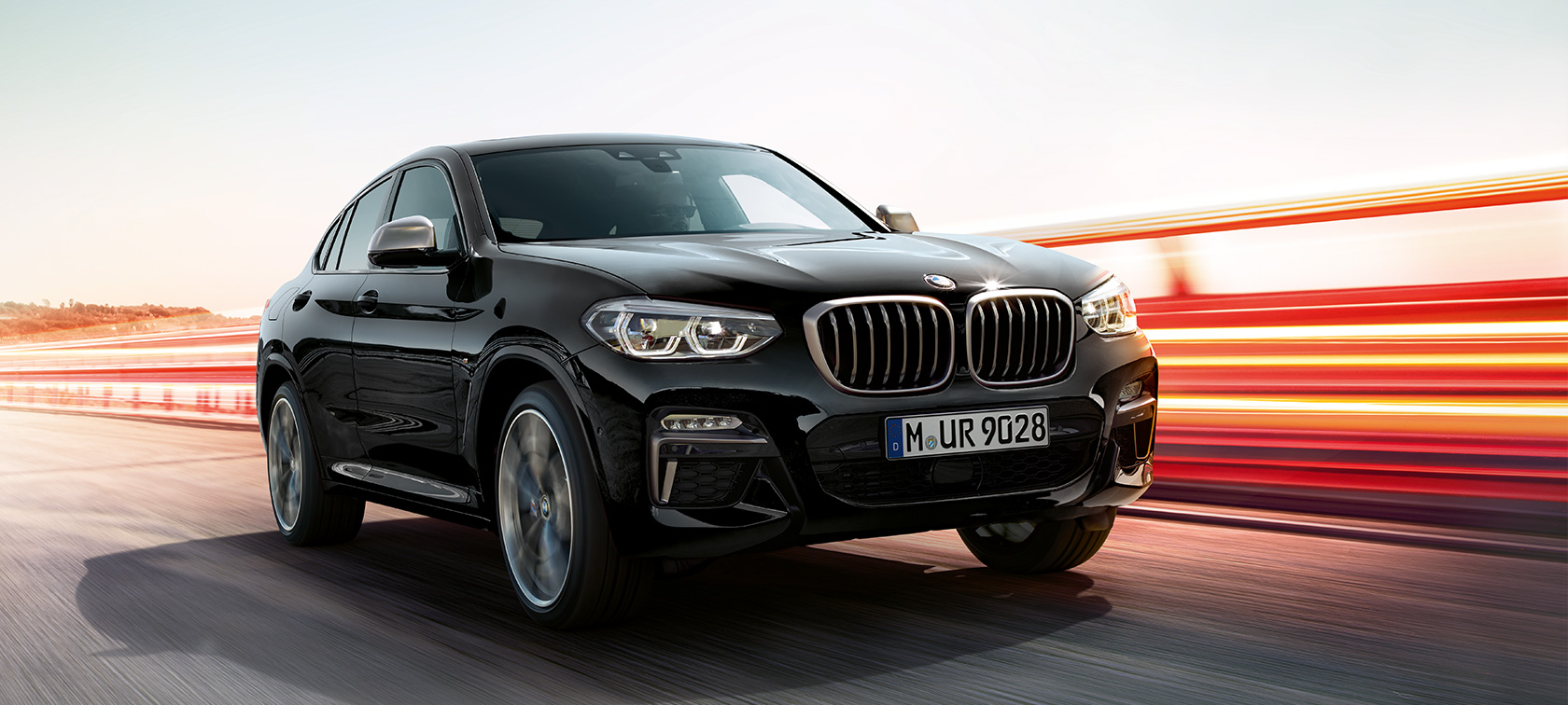BMW X4 M40i and BMW X4 M40d, three-quarter front view, left side. BMW X4 M40i and BMW X4 M40d in Black Sapphire metallic, exterior, three-quarter front view, left side, with light strips.