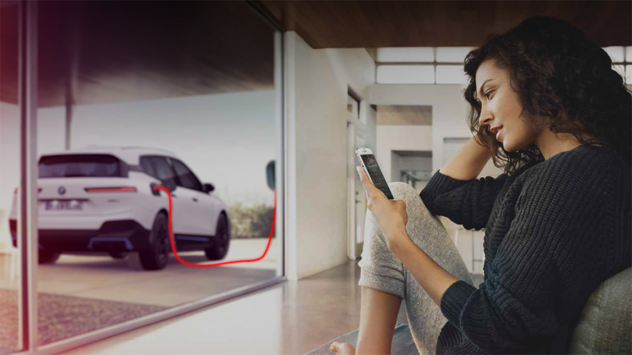 Charging at home BMW iX i20 Frau mit Smartphone