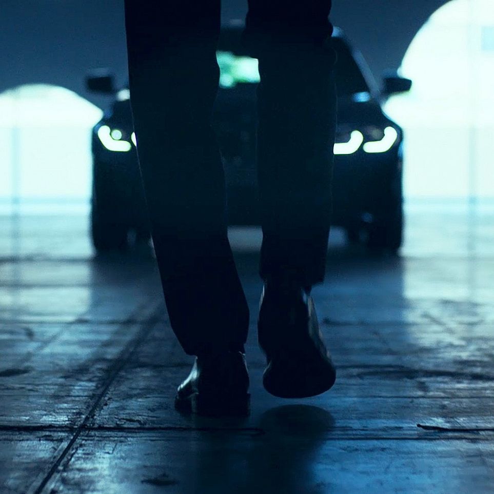 BMW 3 Series Sedan, Front. View from behind of walking man in front of the BMW 3 Series Sedan on asphalt.